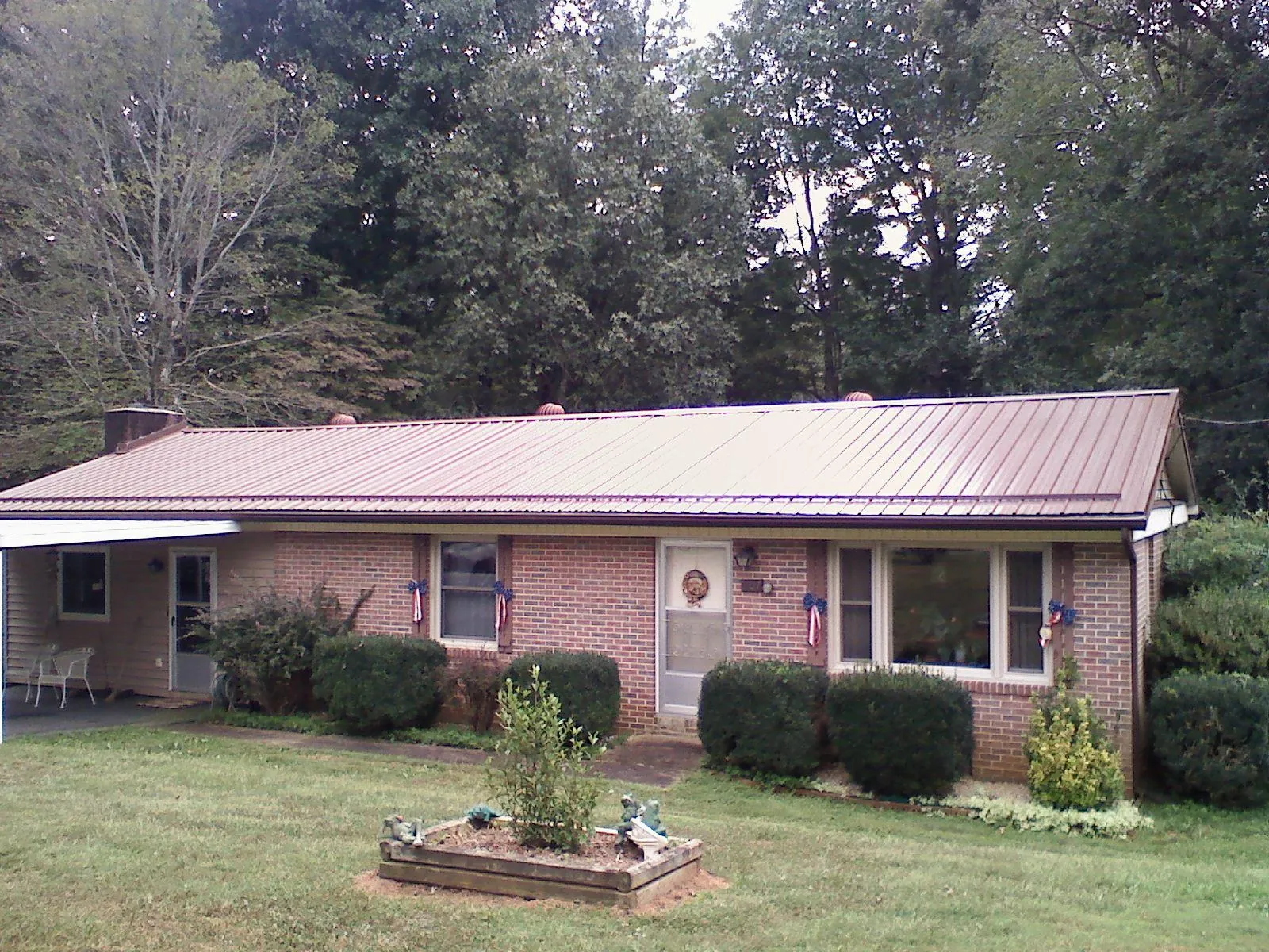 Bronze metal roof on a brick ranch home with a carport in Bronxville