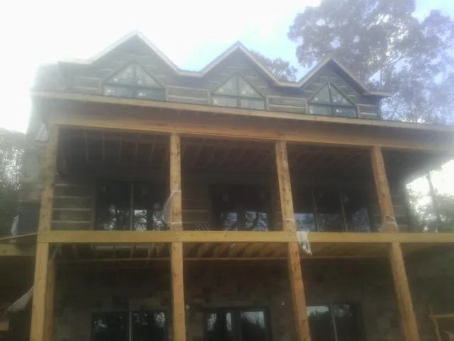 Dormers and porch framing on a large log home under construction — Roof Coating work by our crew in Bronxville