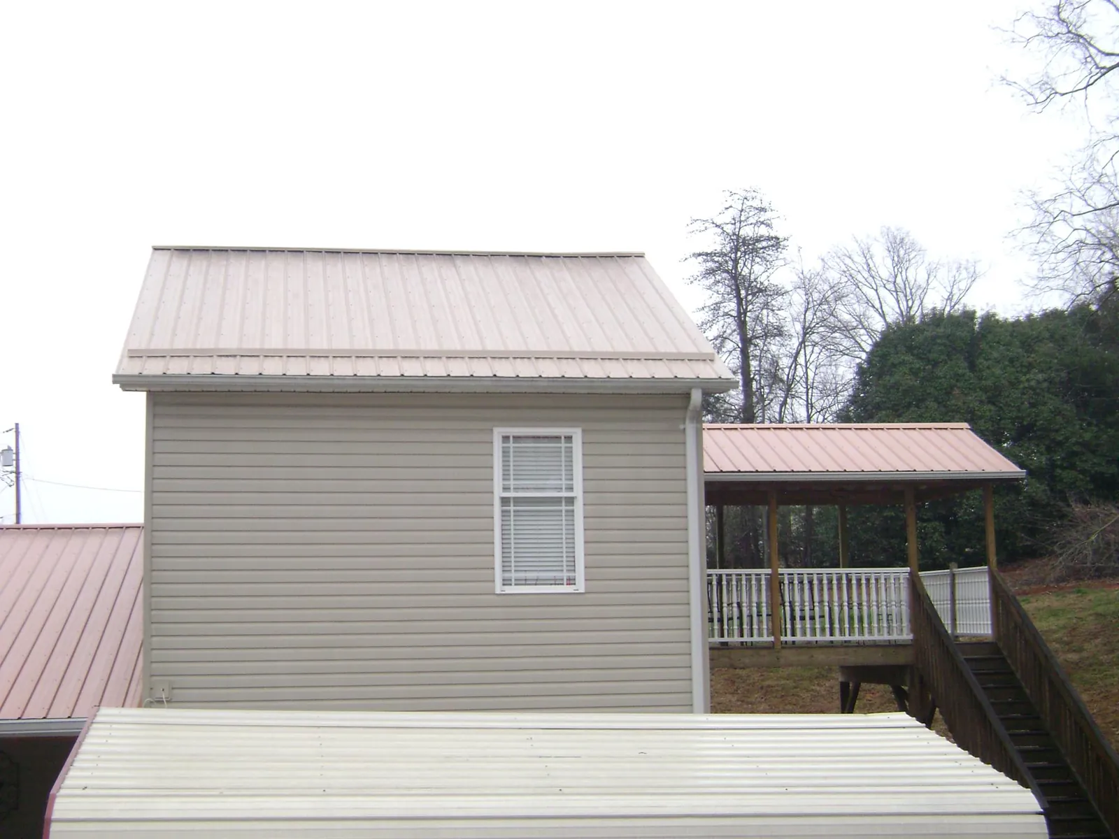 Tan metal roofs on a two story addition and attached porch, from a Roof Replacement job in Bronxville