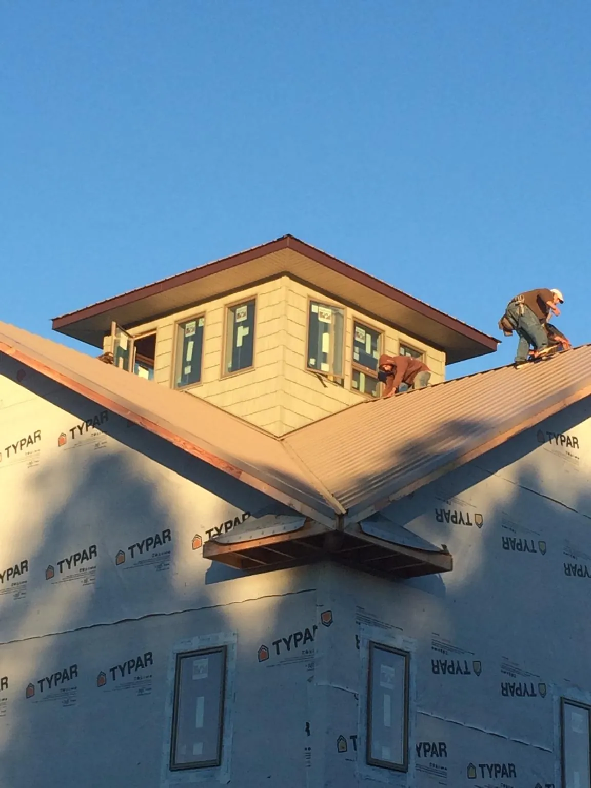 Roofers working around a rooftop cupola on a new metal roof at sunset — Roof Waterproofing in Bronxville by Roofing Brothers